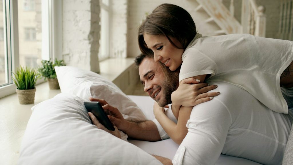 Coppia a letto che usa un’app sul telefono