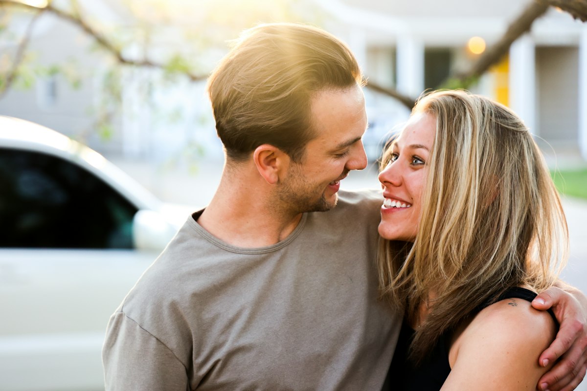 Una coppia si abbraccia sorridendo all’aperto