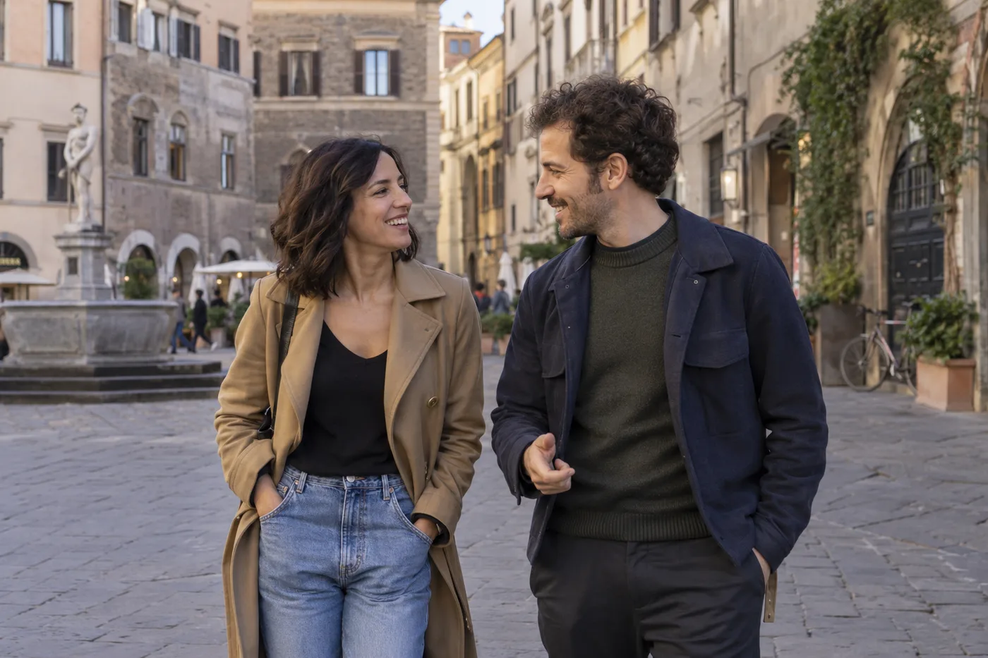 Una donna e un uomo passeggiano e conversano in una piazza italiana